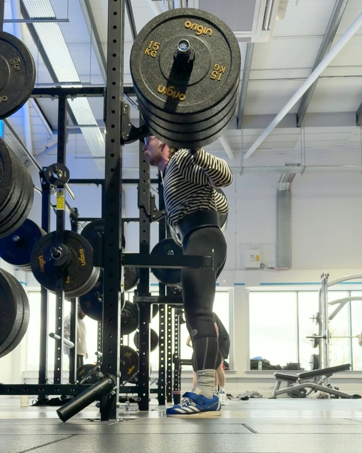 Balazs Morvay standing up out of a barbell back squat in the rack